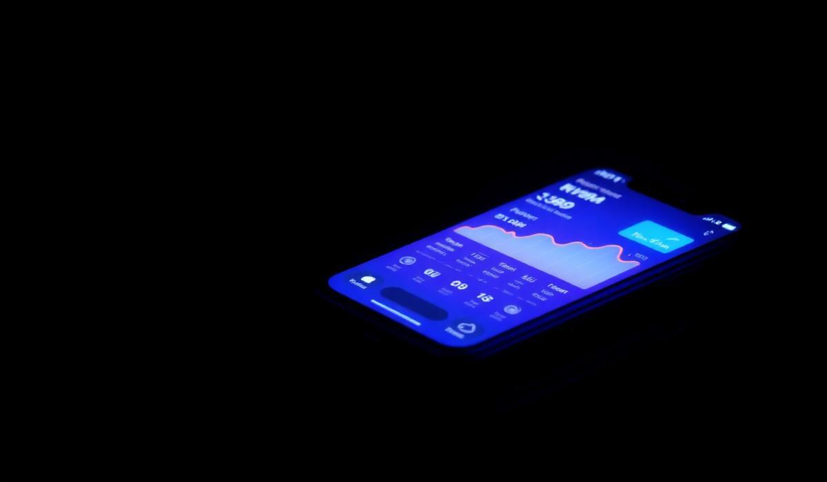 Smartphone displaying a glowing fintech app with payment graph in dark setting